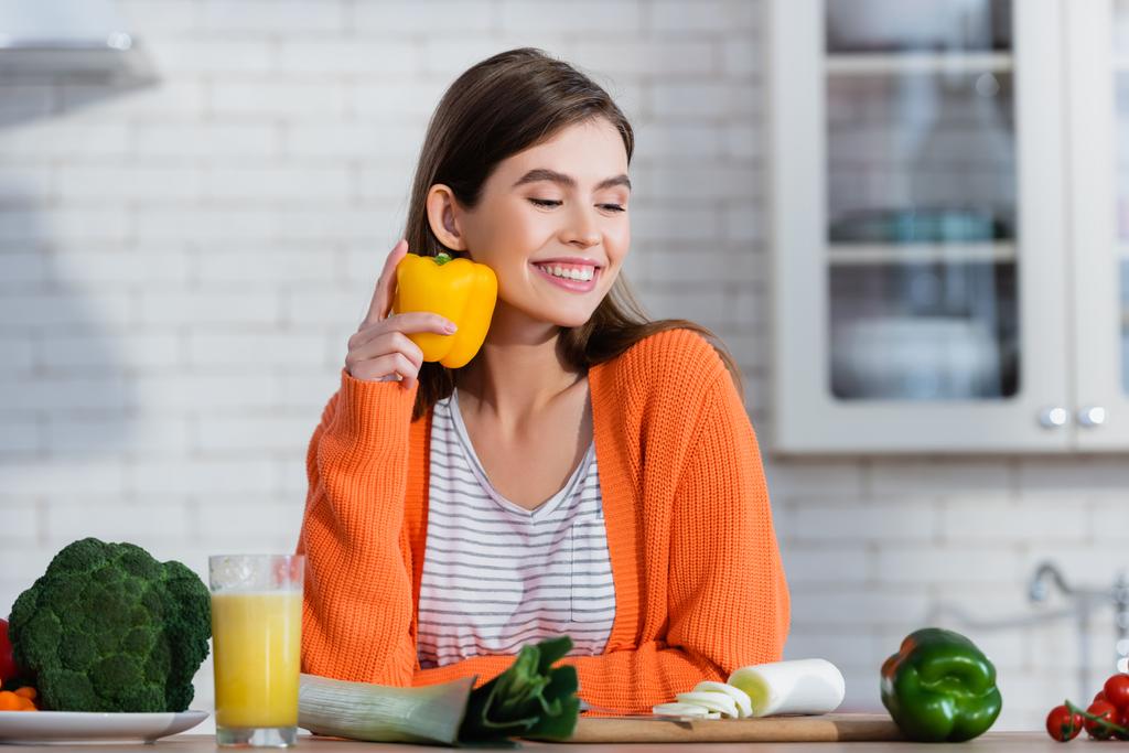 femme heureuse tenant poivron près des légumes frais et un verre de jus - Photo, image