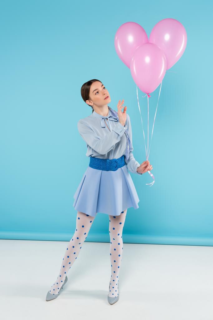mulher na moda em meias pontilhadas segurando balões rosa no fundo azul - Foto, Imagem