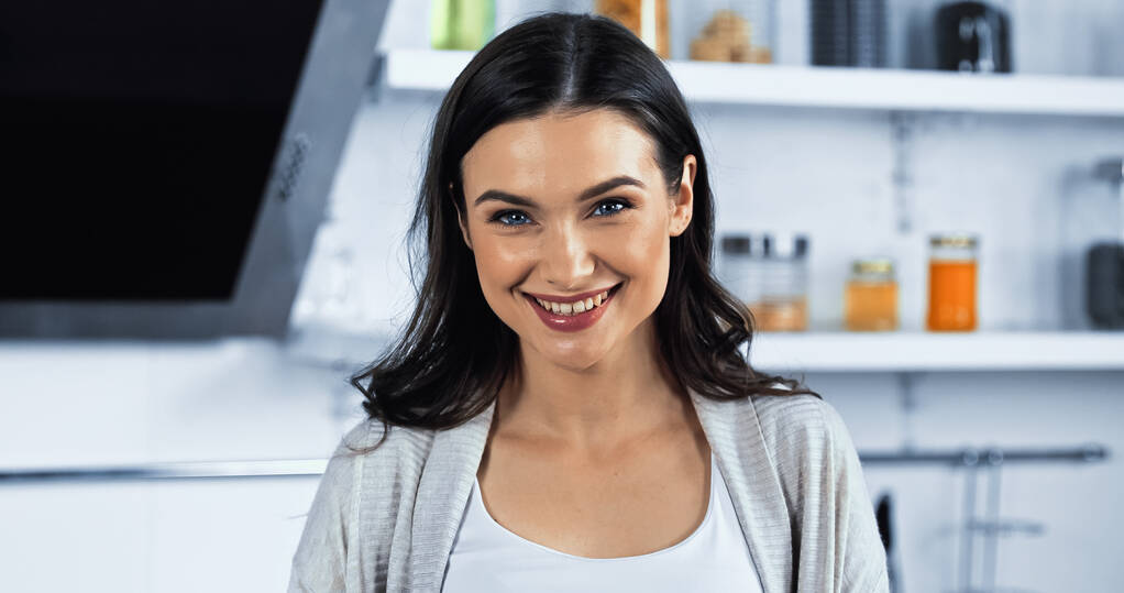 Brunette vrouw glimlachen op camera in de keuken  - Foto, afbeelding