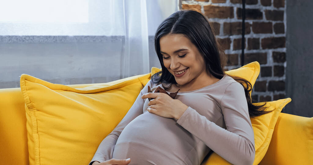 Χαρούμενη έγκυος γυναίκα κρατώντας κεκάκι στο σπίτι  - Φωτογραφία, εικόνα
