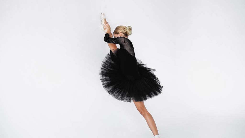 bailarina flexible en falda de tutú y zapatos puntiagudos que se estiran sobre fondo blanco  - Foto, imagen