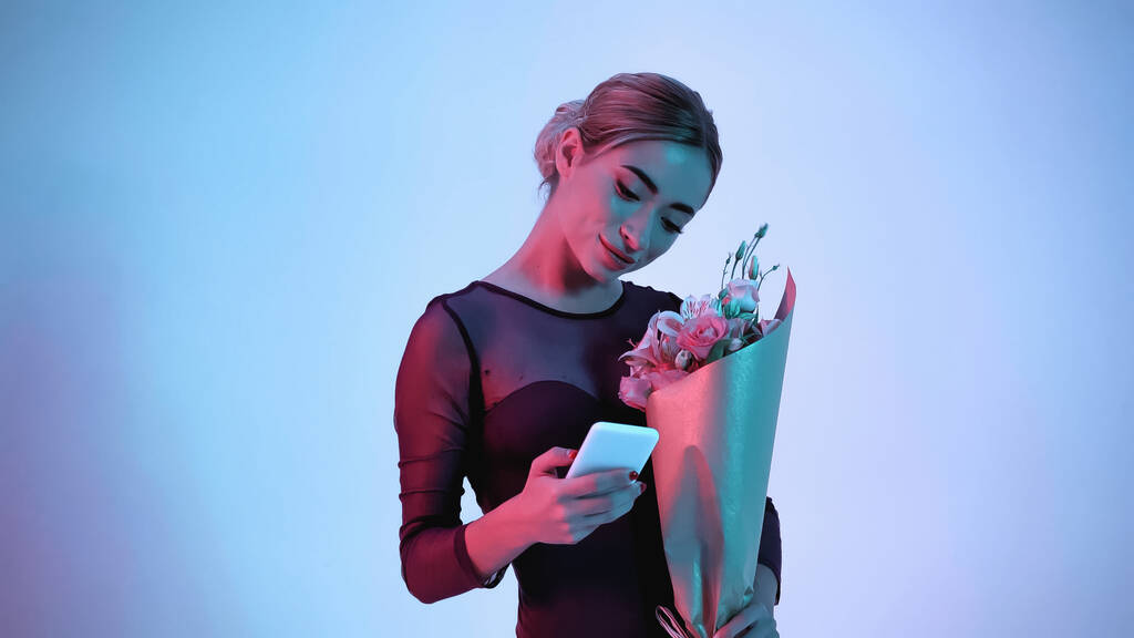 Ballerina mit Blumen und Smartphone auf blau  - Foto, Bild