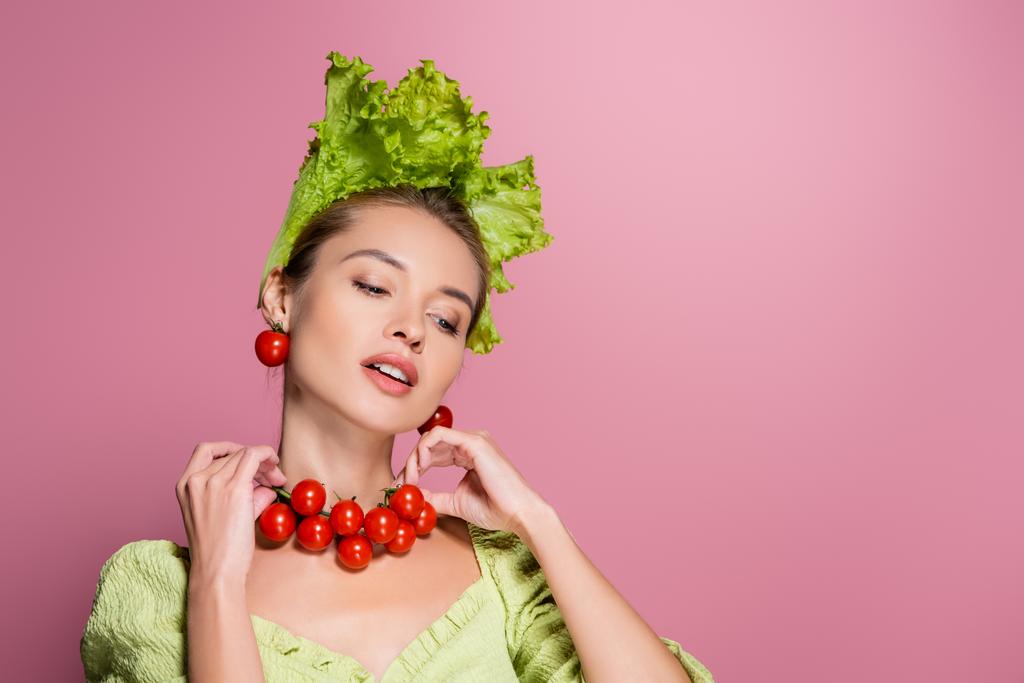 charmante femme en chapeau de laitue, touchant collier fou de tomates gaies sur rose - Photo, image