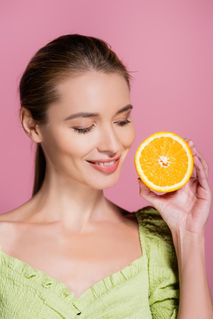 mulher bonita com maquiagem natural segurando metade de laranja madura isolada em rosa - Foto, Imagem