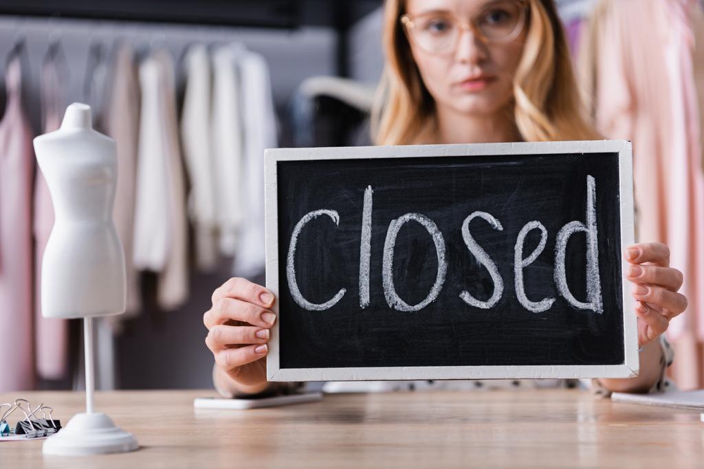 zakenvrouw holding board met gesloten belettering in showroom, wazig achtergrond - Foto, afbeelding