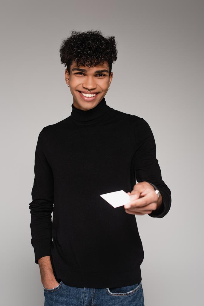 happy african american man in turtleneck sweater giving blank card isolated on grey - Photo, Image