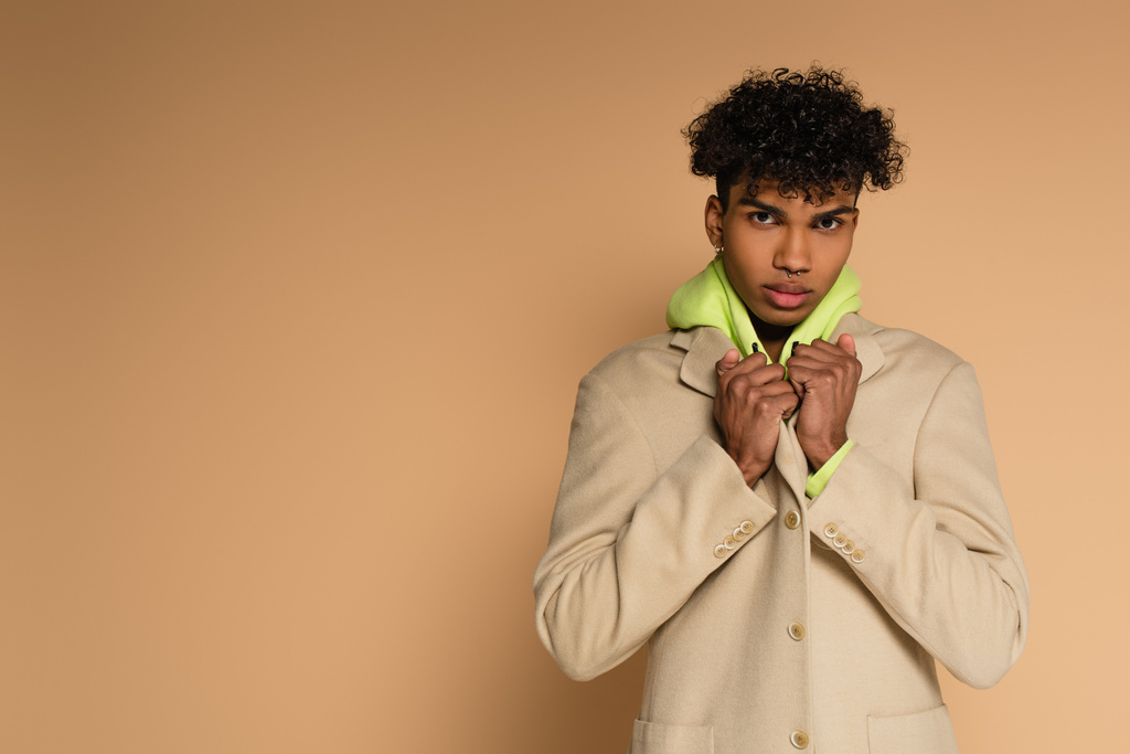 young african american man adjusting blazer on beige - Photo, Image