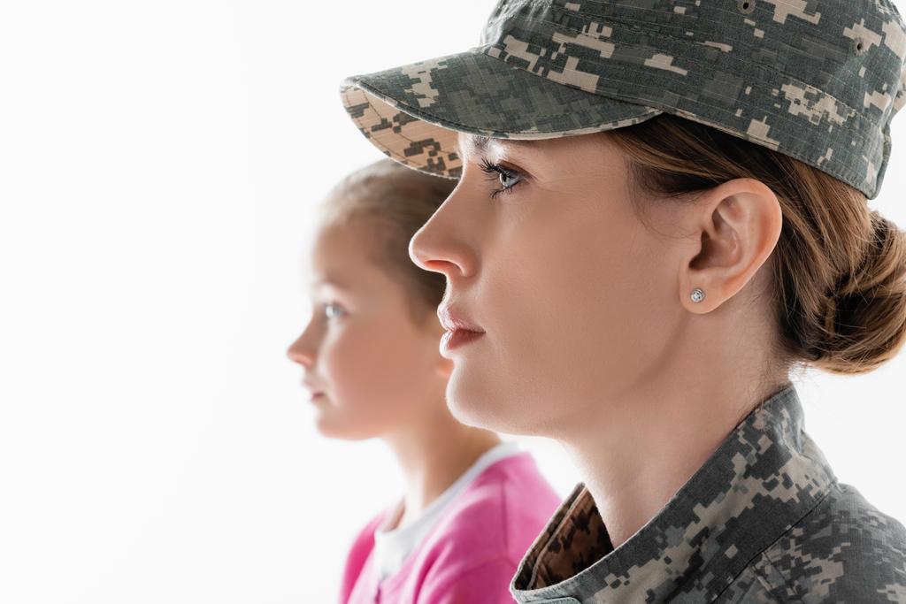 Zijaanzicht van soldaat weg te kijken in de buurt dochter op wazige achtergrond geïsoleerd op wit  - Foto, afbeelding