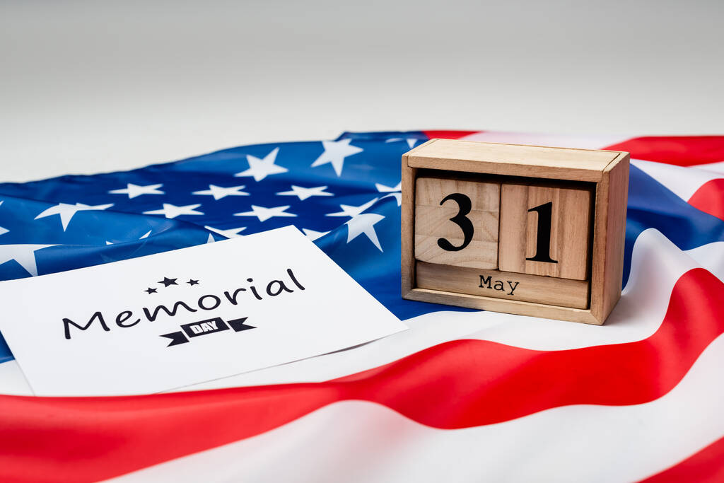 Card with memorial day lettering, wooden calendar and american flag on grey background  - Photo, Image