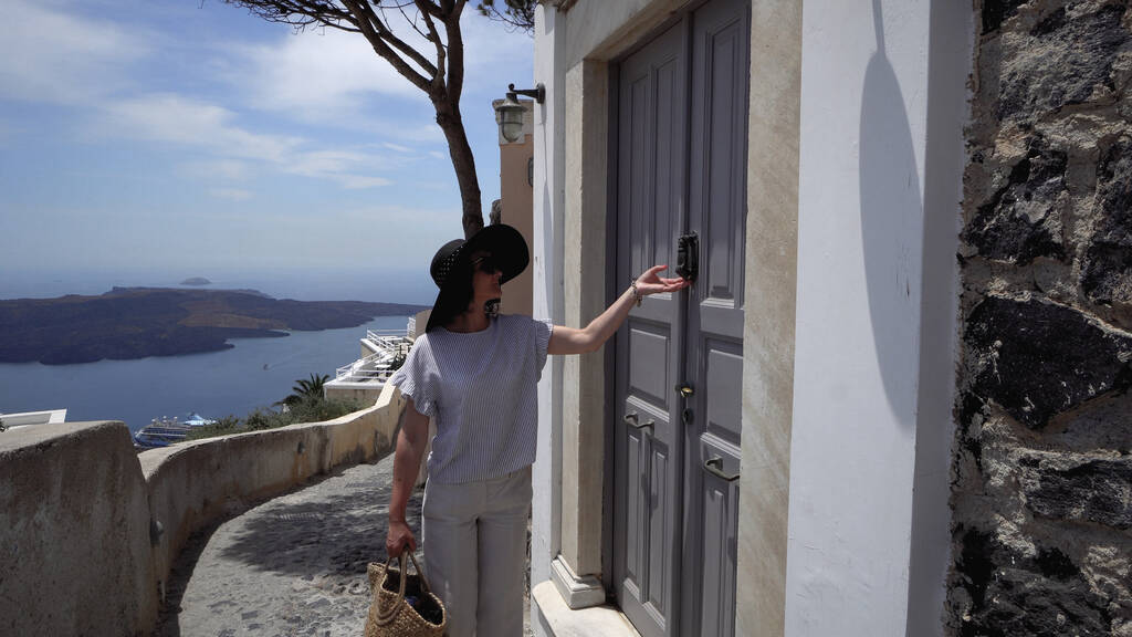 Mujer visitante caminar en la calle Santorini y llamar a la puerta vieja golpeador - Foto, Imagen