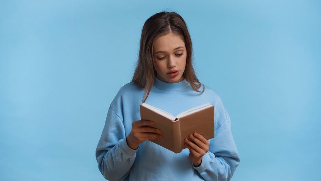 nastolatka dziewczyna w bluzie czytanie powieści izolowane na niebieski - Zdjęcie, obraz