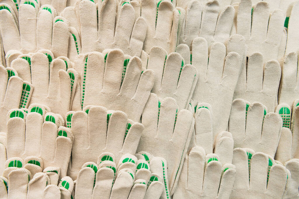Hintergrund aus weißen, identischen Baumwollhandschuhen mit gummierten Punkten, Ansicht von oben - Foto, Bild