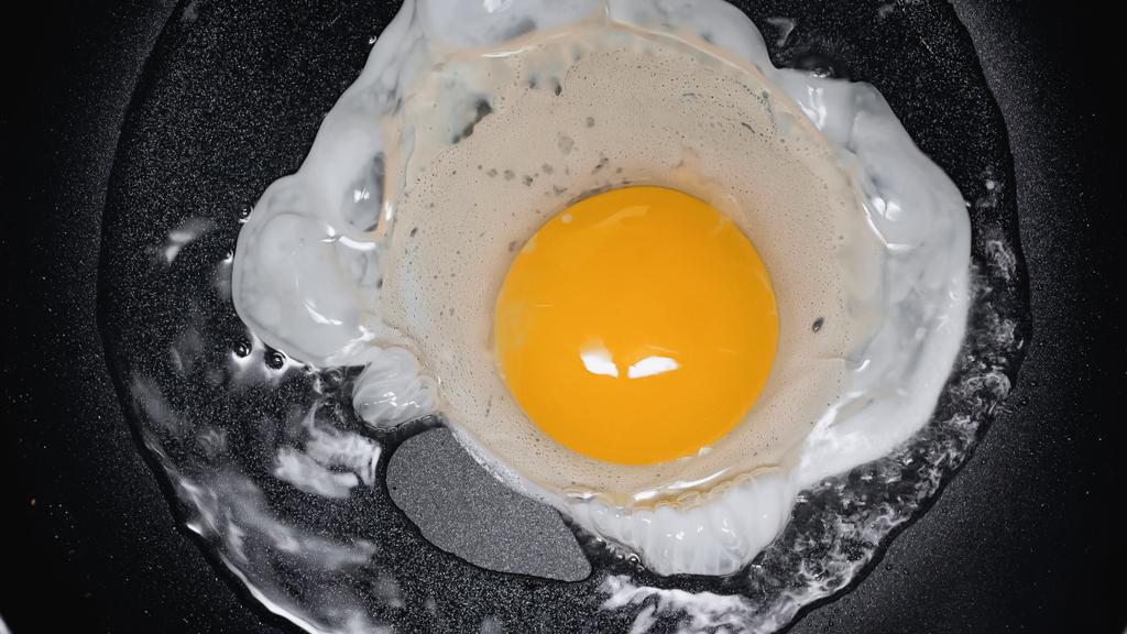 close up of frying egg on frying pan with oil - Fotografie, Obrázek