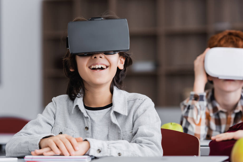 excited boy laughing in vr headset near classmate on blurred background - Photo, Image