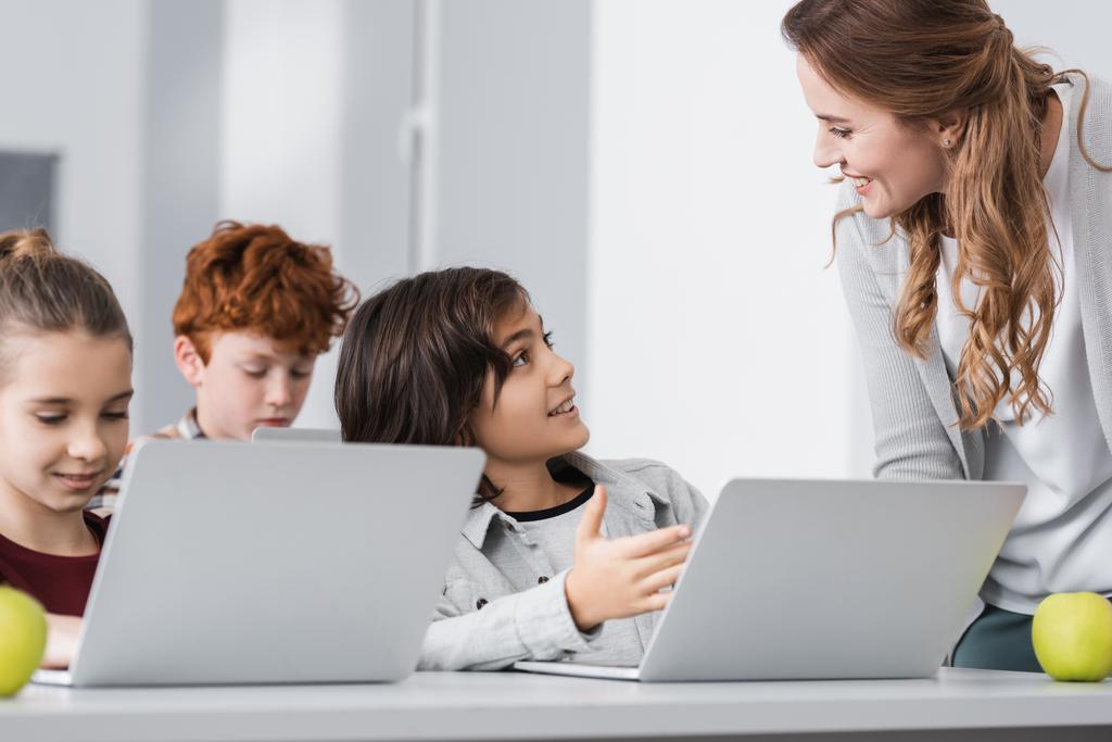 школярка вказує на ноутбук біля усміхненого вчителя в класі
 - Фото, зображення