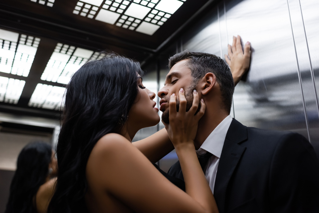 Donna appassionata che tocca il viso del fidanzato in tuta in ascensore  - Foto, immagini