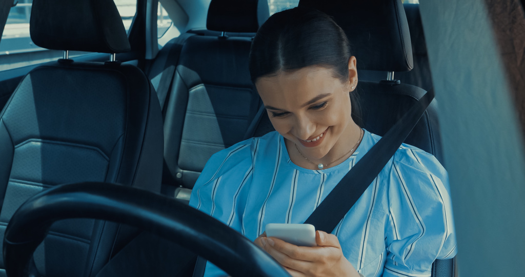 szczęśliwa młoda kobieta smsowanie na smartfonie wewnątrz samochodu - Zdjęcie, obraz