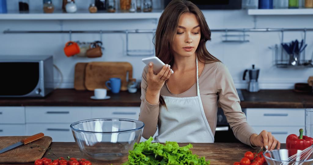 woman using voice assistant while holding smartphone near ingredients  - Photo, Image