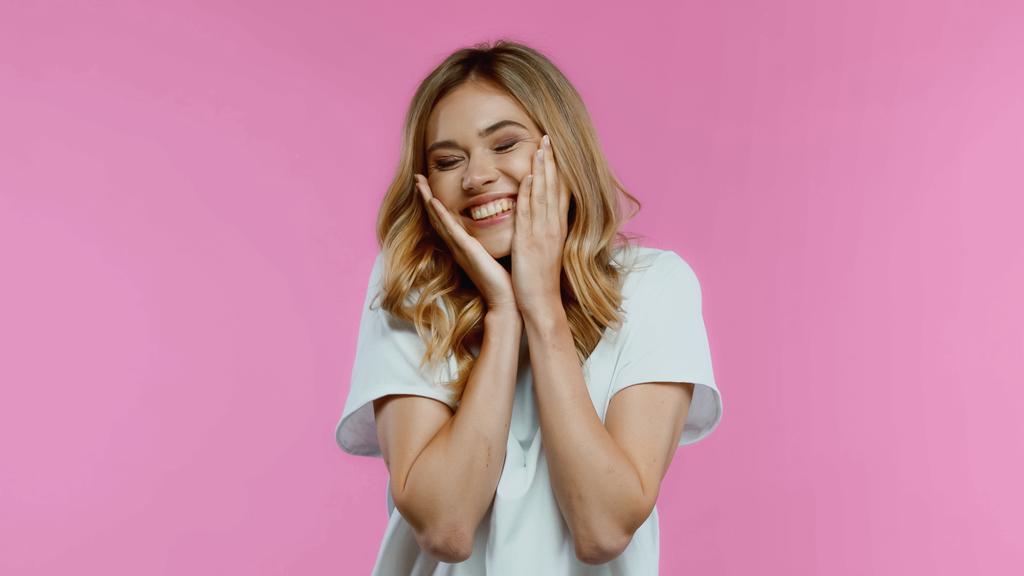 flattered woman touching cheeks and smiling isolated on pink  - Photo, Image