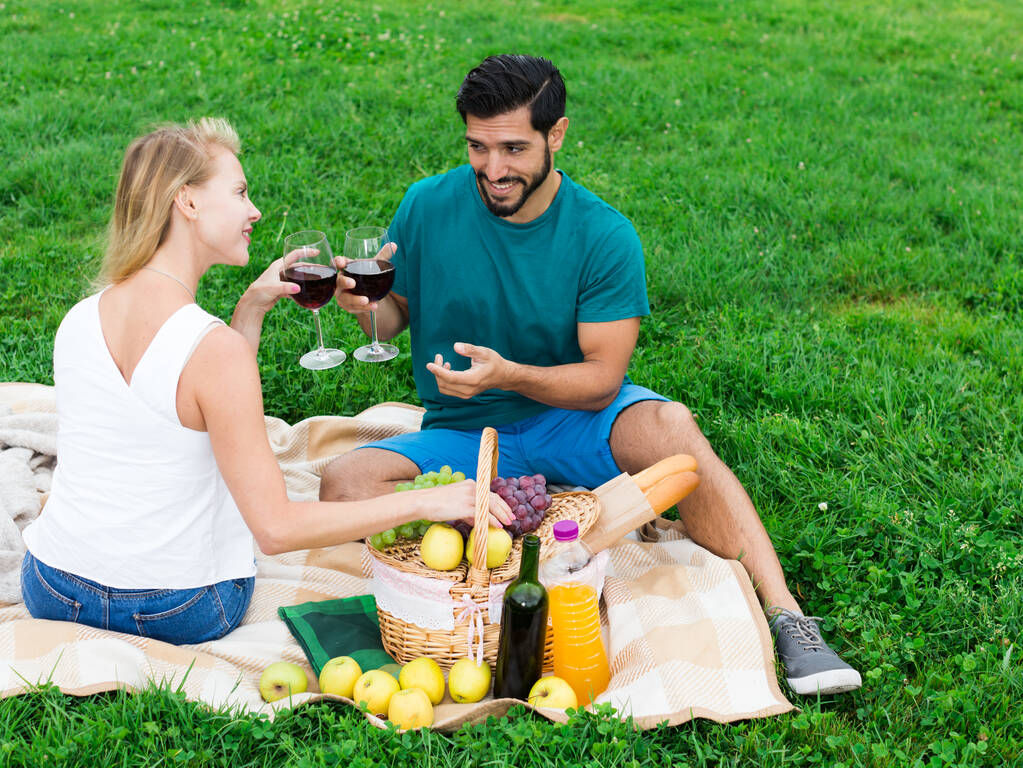 Άνδρας και γυναίκα κάθονται και χαλαρώνουν με ποτήρια κρασιού - Φωτογραφία, εικόνα