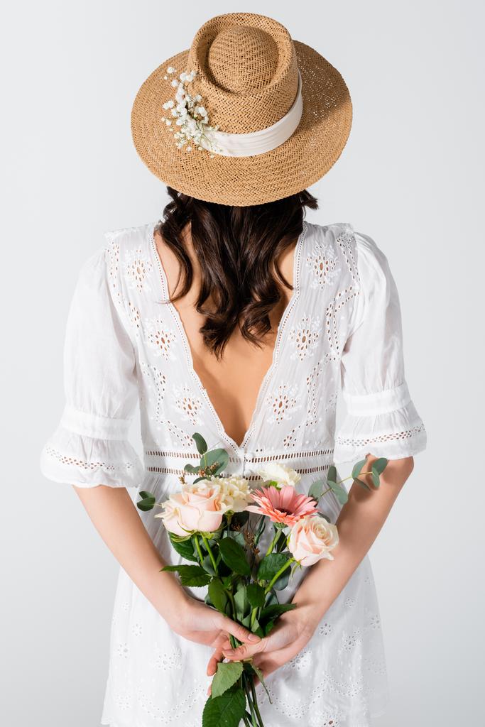 back view of woman in straw hat and dress holding bouquet isolated on white - Photo, Image