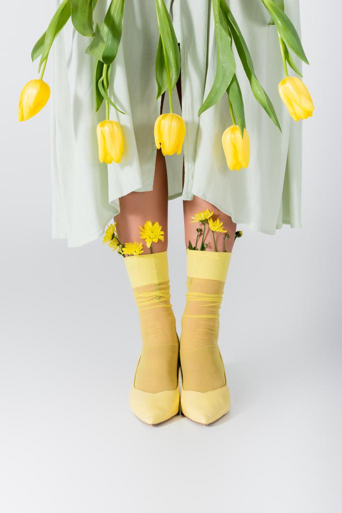частичный вид женщины в юбке с желтыми тюльпанами, изолированными на белом - Фото, изображение