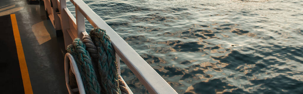 Cuerda en barandilla del barco con agua de mar en el fondo, bandera  - Foto, imagen