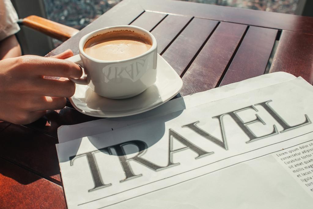 vista parcial del hombre cerca de la taza de café y periódico de viajes en la cafetería - Foto, Imagen