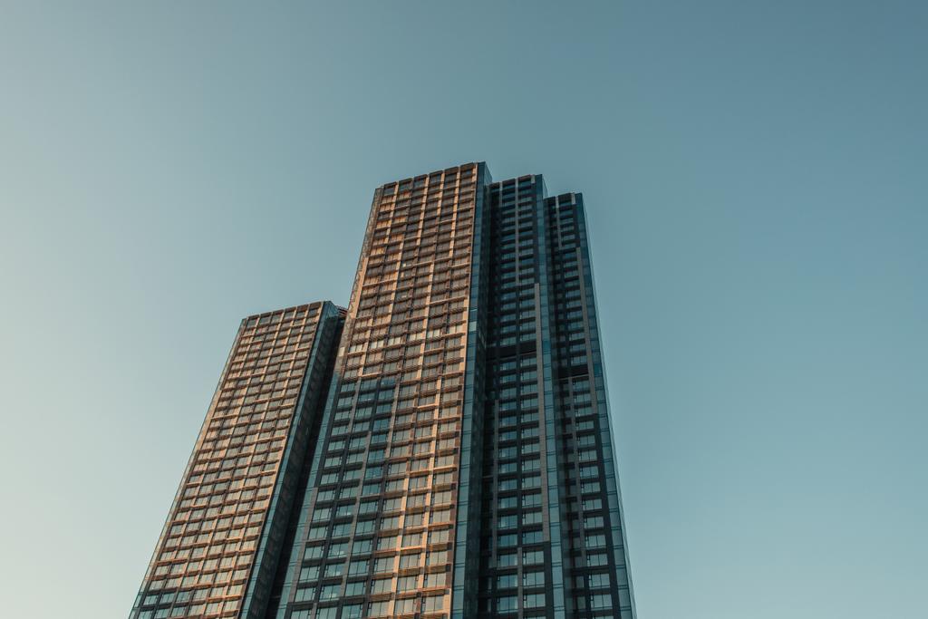 Mavi gökyüzüne karşı çok katlı binanın düşük açılı görüntüsü  - Fotoğraf, Görsel