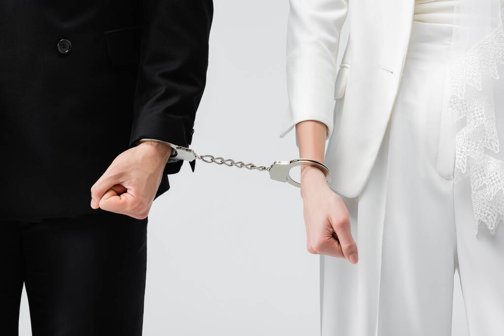 Обрізаний вигляд нареченого і нареченого в наручниках ізольовані на сірому
  - Фото, зображення