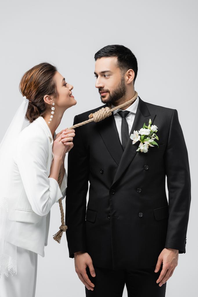 усміхнена наречена тягне ковзаючий вузол на шию арабського нареченого ізольовано на сірому
  - Фото, зображення