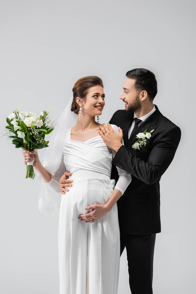 ムスリム新郎抱擁妊娠中の花嫁ともに結婚式花束孤立オングレー  - 写真・画像