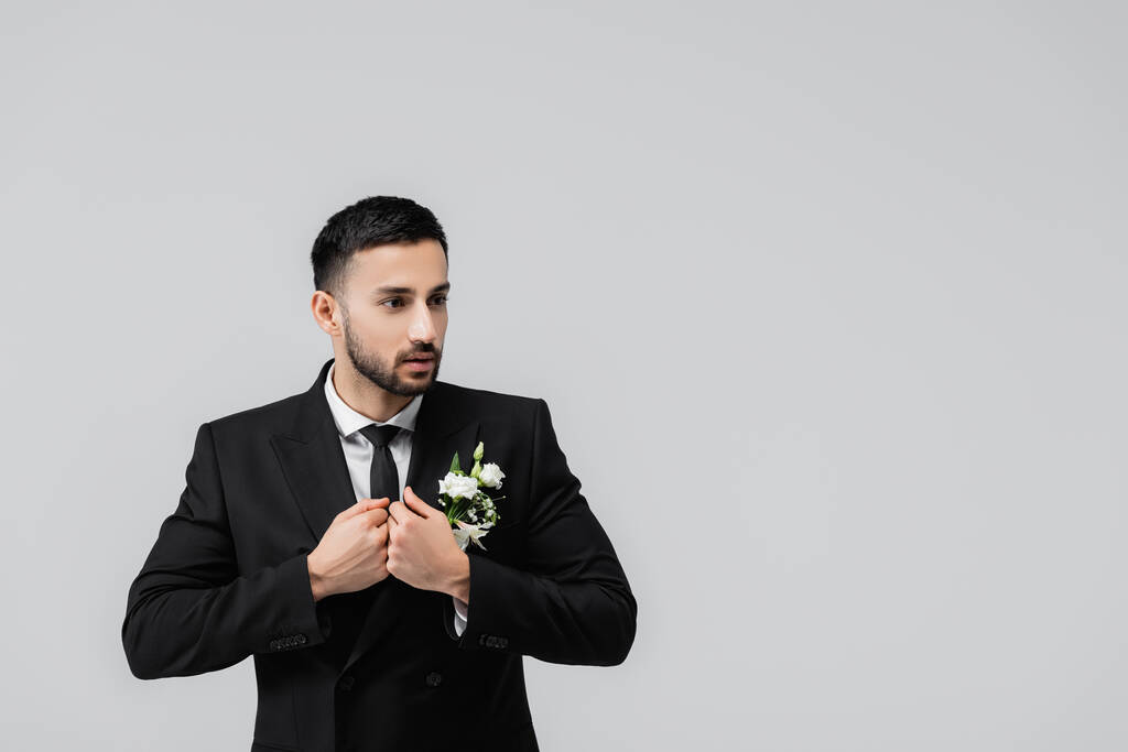 Arabischer Bräutigam schaut weg, während er Jacke isoliert auf grau trägt  - Foto, Bild