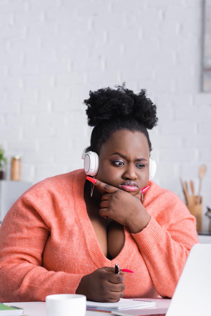 pensativo africano americano más tamaño mujer en auriculares inalámbricos escuchar podcast  - Foto, imagen