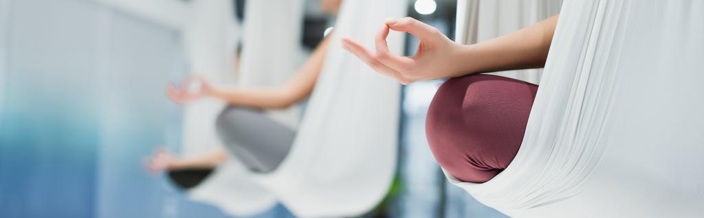 vista cortada de mulheres meditando em pose de lótus em redes aéreas de ioga, fundo borrado, banner - Foto, Imagem