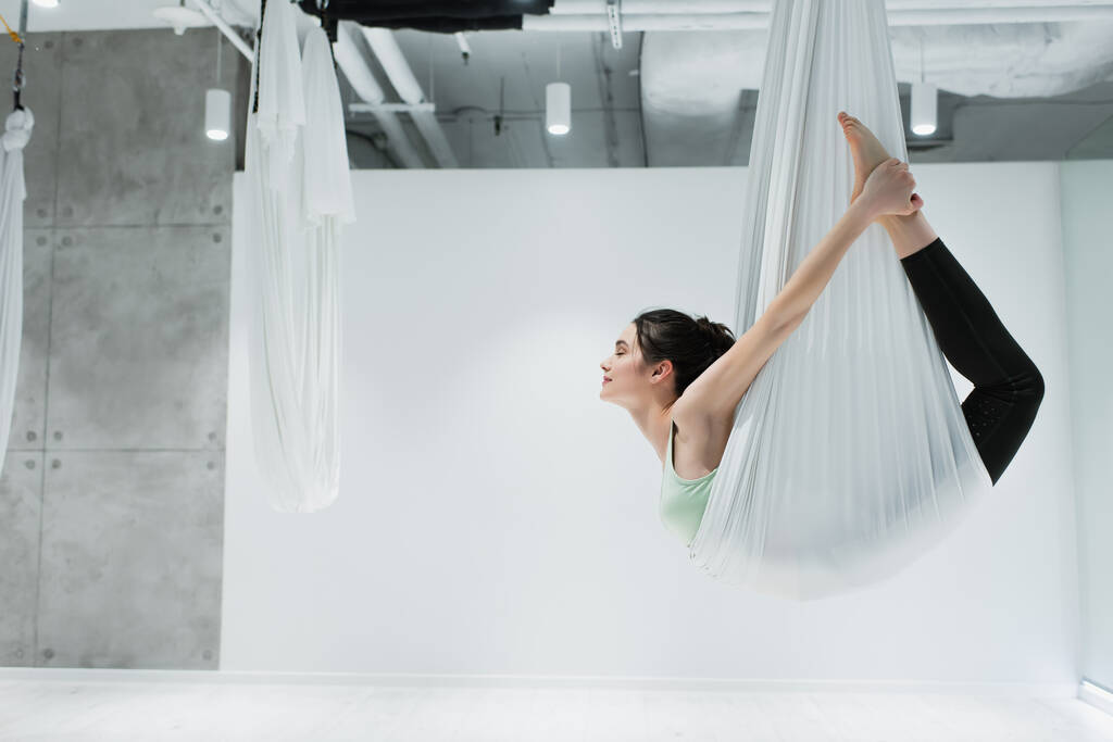 Вид збоку жінки, що тягнеться з мухами йоги
  - Фото, зображення
