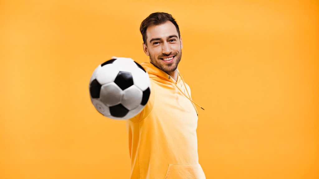 χαμογελαστός άντρας που παίζει με το ποδόσφαιρο απομονωμένος στο κίτρινο - Φωτογραφία, εικόνα