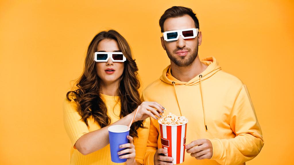 boyfriend and girlfriend watching movie in 3d glasses isolated on yellow  - Photo, Image