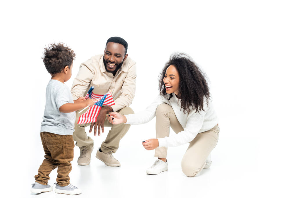 afro-américain garçon tenant de petits drapeaux des Etats-Unis près de rire parents n blanc - Photo, image