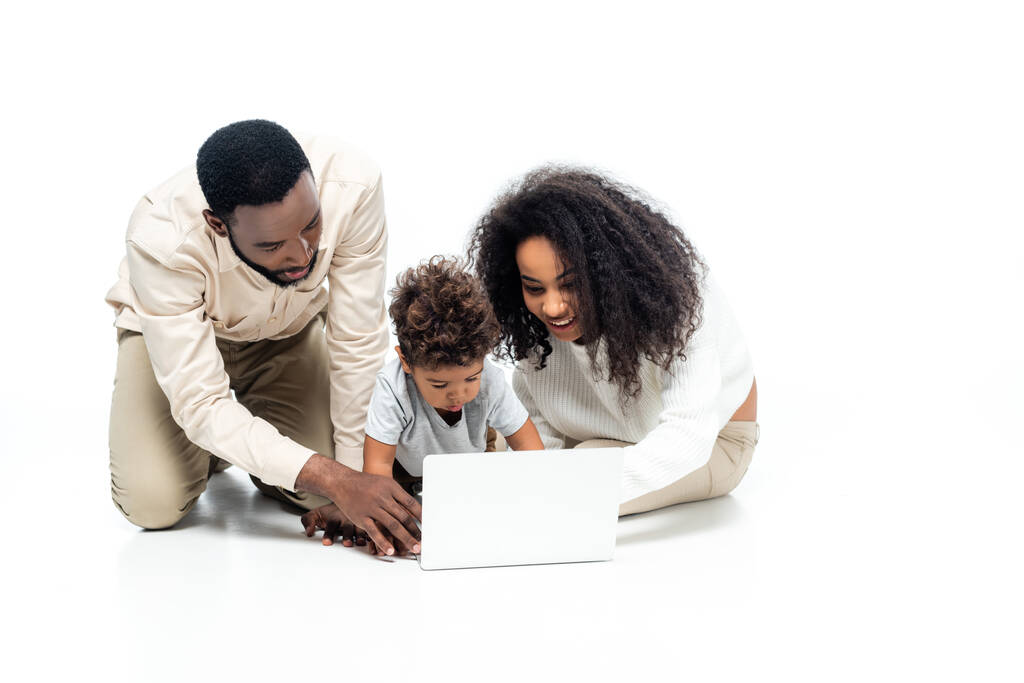 Αφροαμερικανοί ζευγάρι που χρησιμοποιούν το lap-top μαζί με το γιο νήπιο στα λευκά - Φωτογραφία, εικόνα