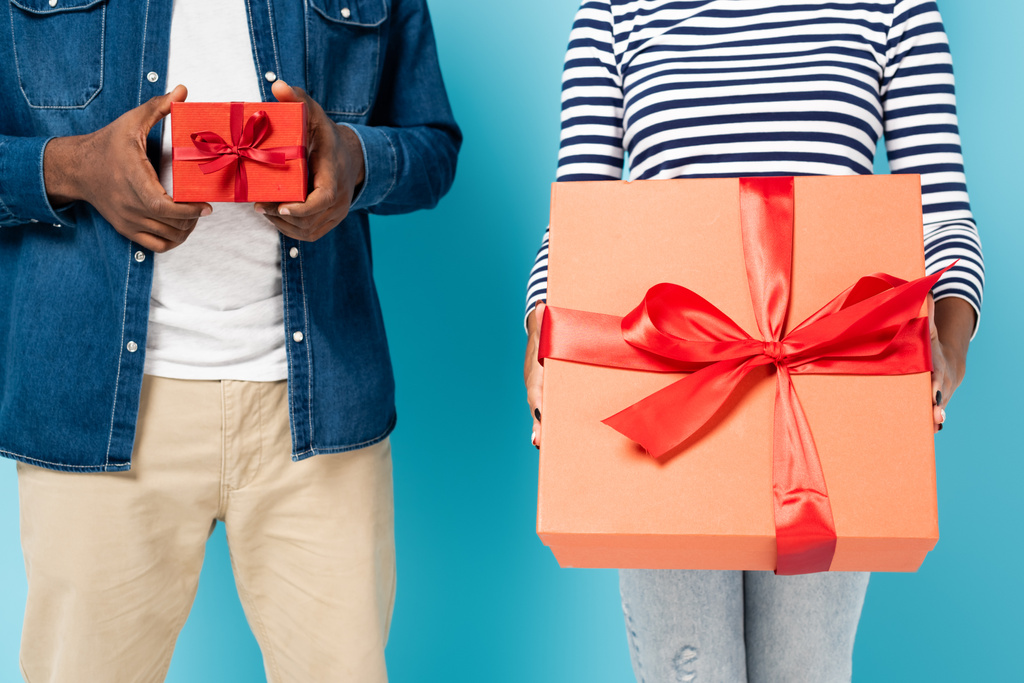 vista recortada de pareja afroamericana sosteniendo cajas de regalo grandes y pequeñas en azul - Foto, imagen