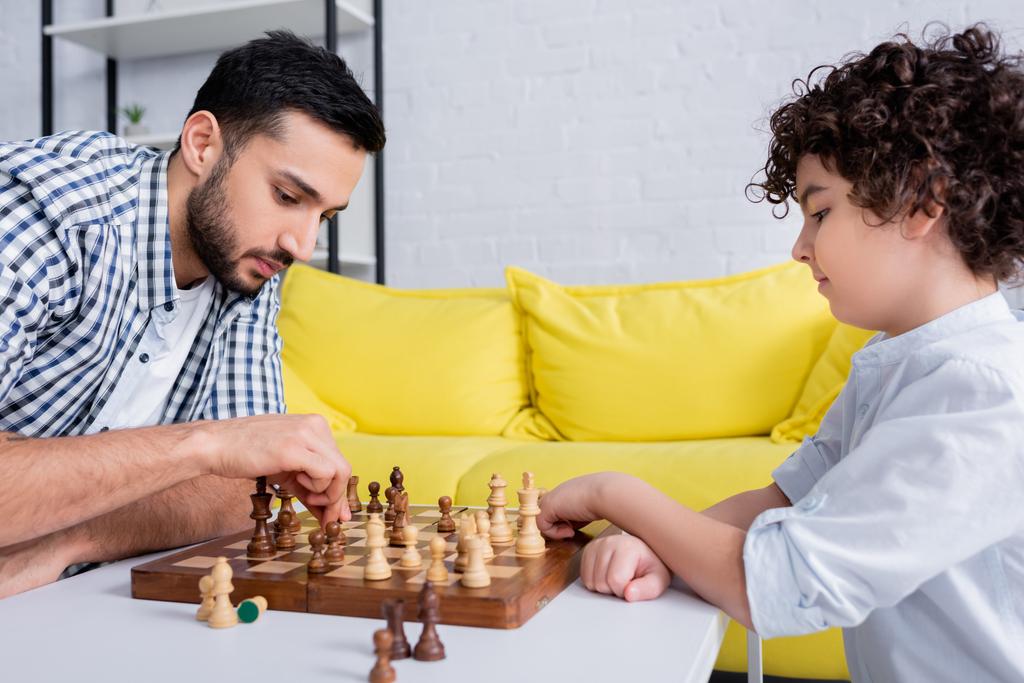 Арабский мужчина играет в шахматы с сыном дома  - Фото, изображение