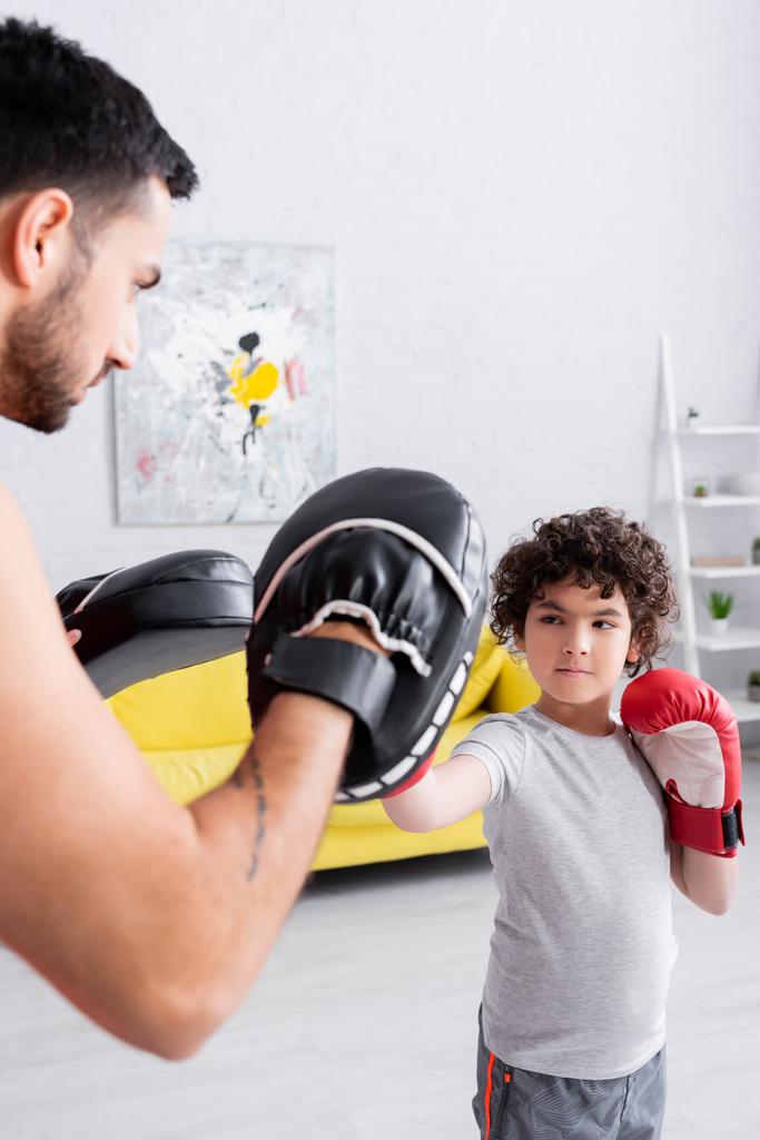 イスラム教徒男の子でボクシング手袋ボクシングとともにお父さんでパンチミットオンぼやけた前景  - 写真・画像