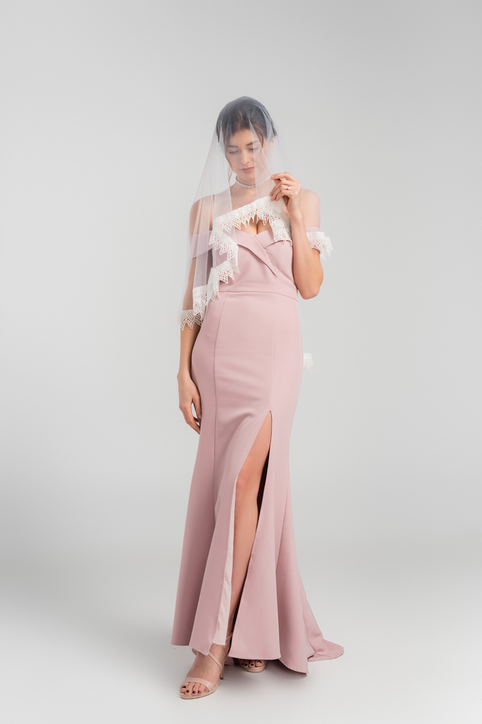 teljes hosszúságú kilátás menyasszony rózsaszín ruha borító arc fátyol szürke - Fotó, kép