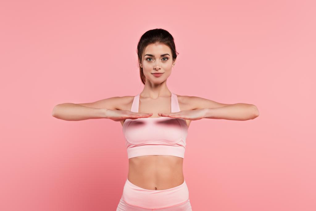 Young fit sportswoman exercising on pink background - Photo, Image