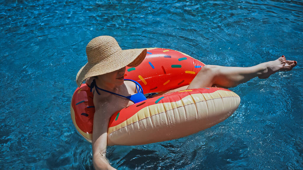 young woman in straw hat swimming in pool with inflatable ring - Photo, Image