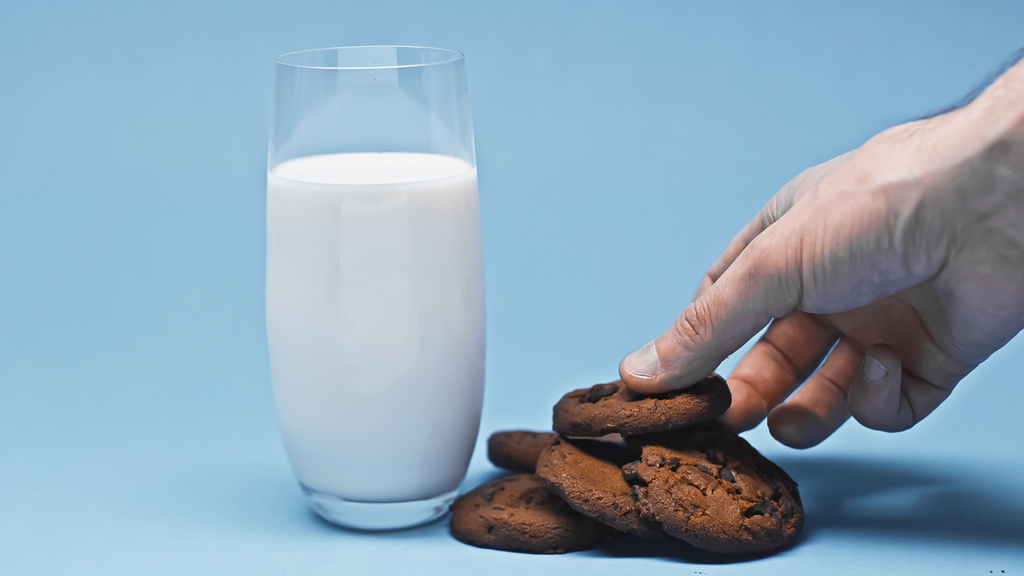 partial view of man taking chocolate cookie near glass with fresh milk - Photo, Image