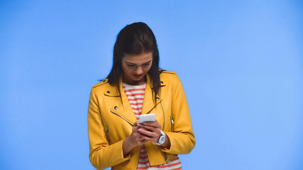 νεαρή γυναίκα κουβεντιάζοντας σε smartphone απομονωμένο σε μπλε - Φωτογραφία, εικόνα