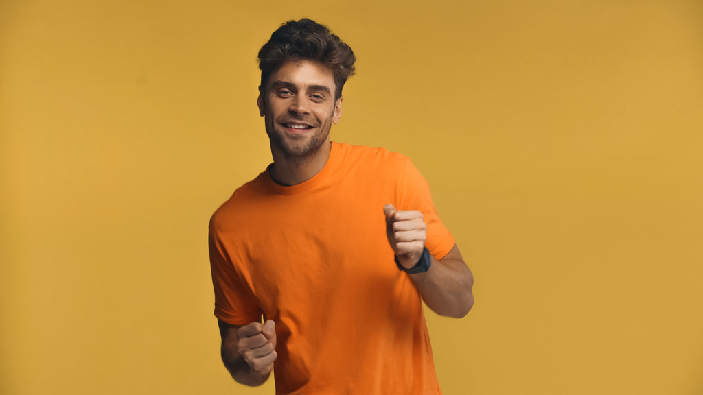 Homme joyeux en t-shirt orange dansant isolé sur jaune - Photo, image