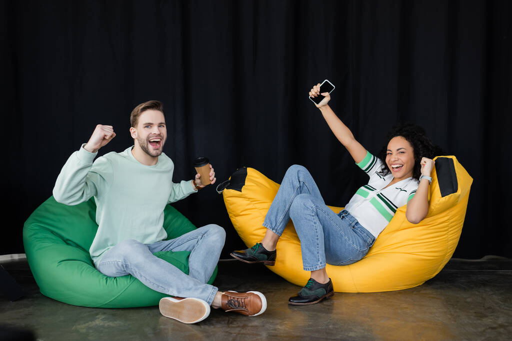 mladí, úspěšní podnikatelé předvádějí vítězné gesto, zatímco sedí v křeslech - Fotografie, Obrázek